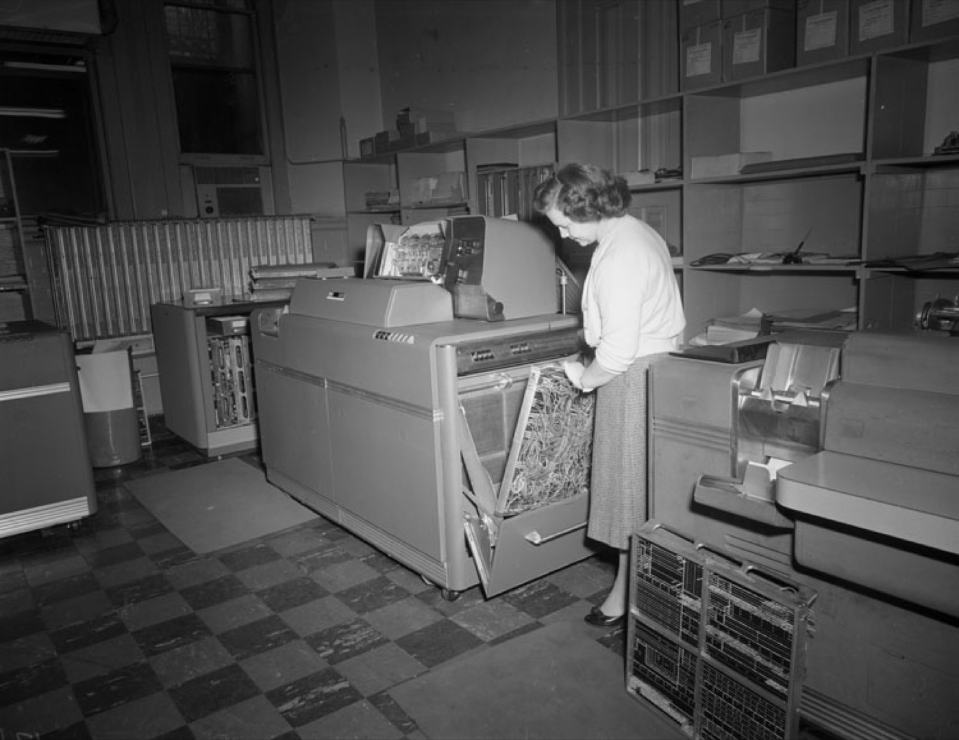 A woman wiring the plugboard of an IBM accounting machine in a punched-card room, 1959.