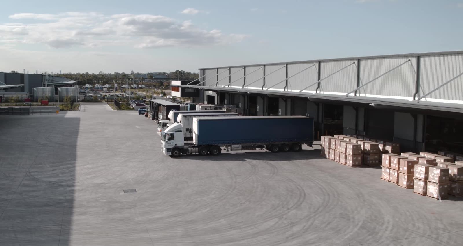 A distribution yard: trucks backed onto the loading docks, pallets stacked on the apron.
