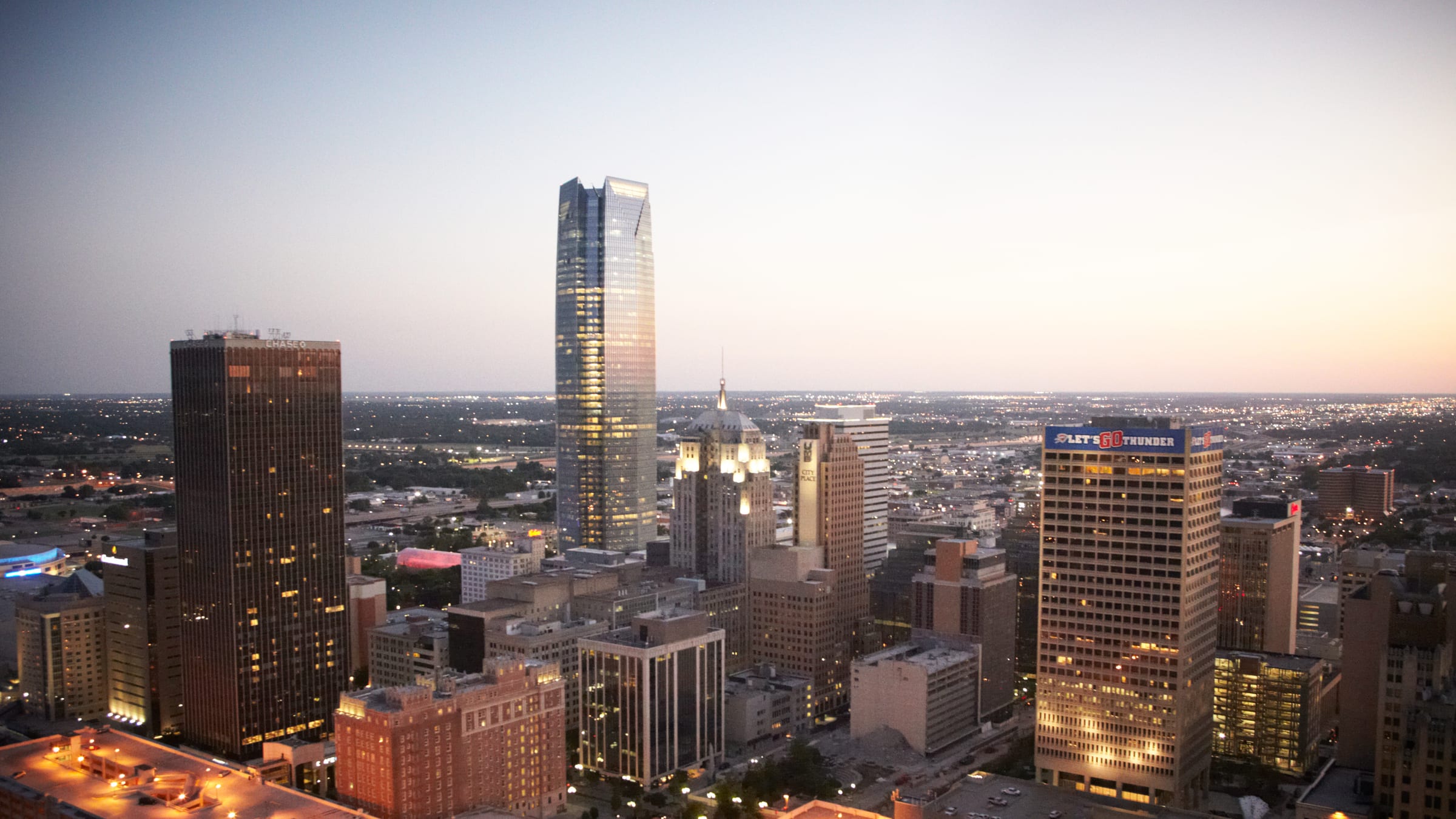 Downtown Oklahoma City at twilight: Devon Tower, lit office towers and glowing rooftops.