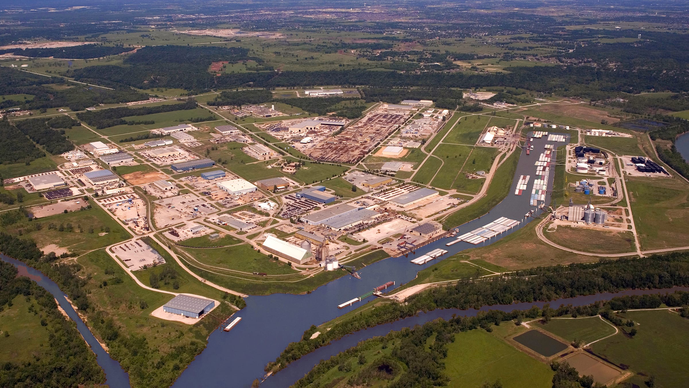 A high aerial of the Tulsa Port of Catoosa industrial park: rows of warehouses along the barge channel, farmland beyond.