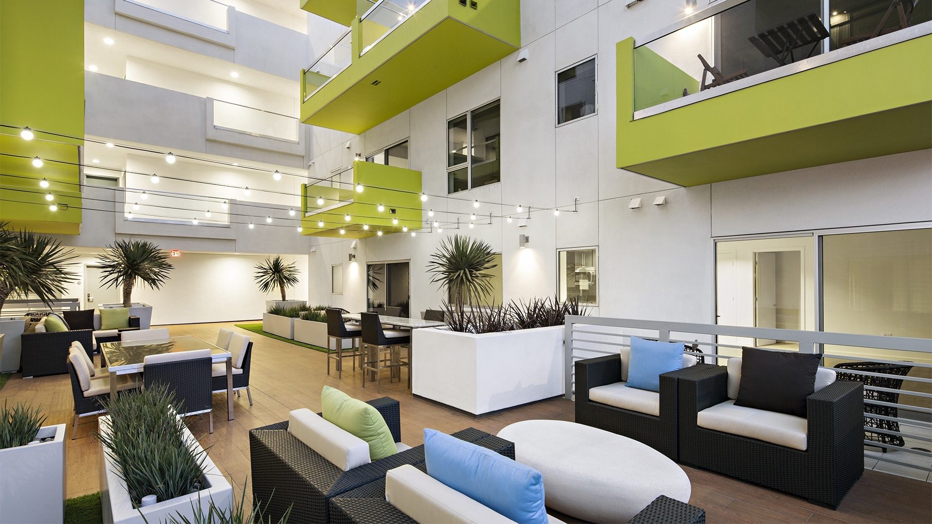 An apartment atrium with lime-green balconies over lounge seating, from the Amoroso portfolio
