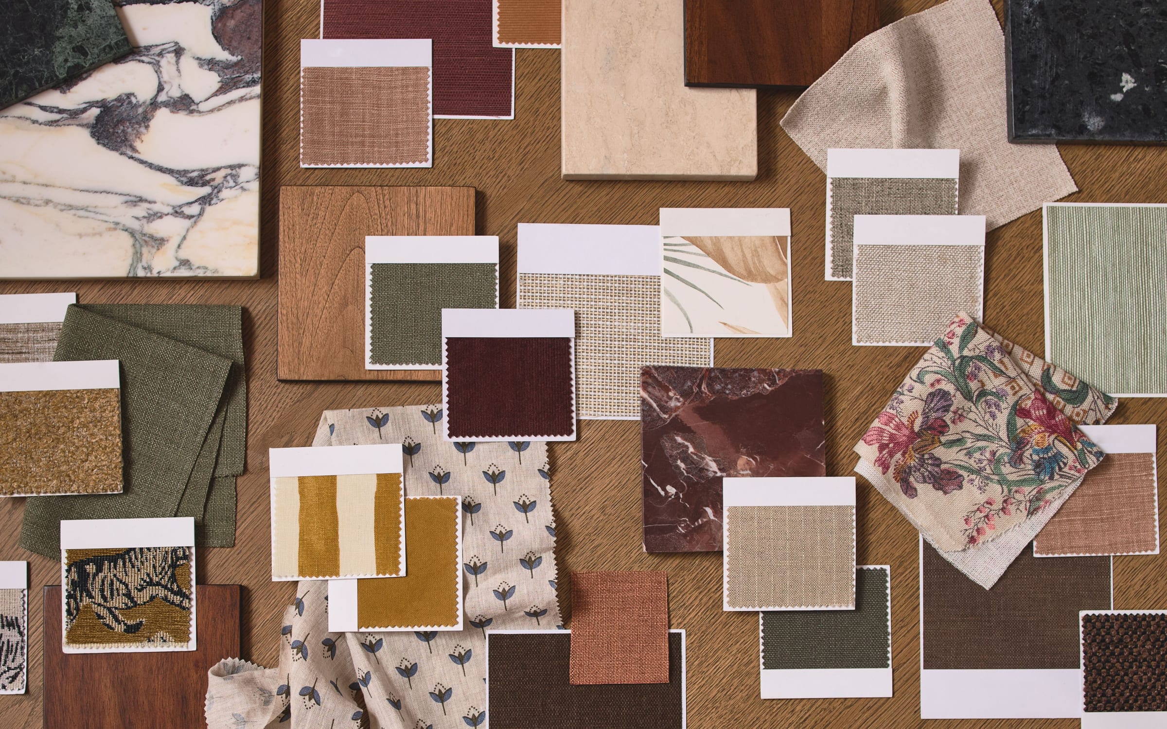 An overhead flat-lay of fabric swatches, wood and tile samples and a marble slab.