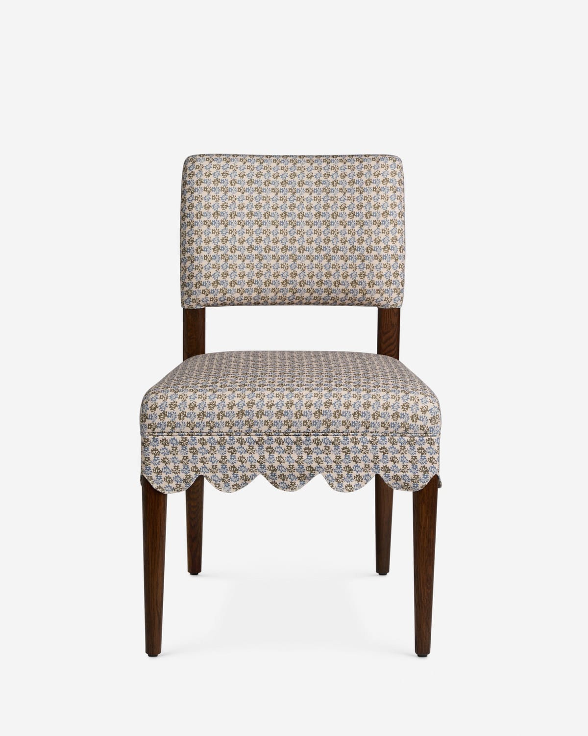A dining chair with a scalloped patterned skirt, shot on white
