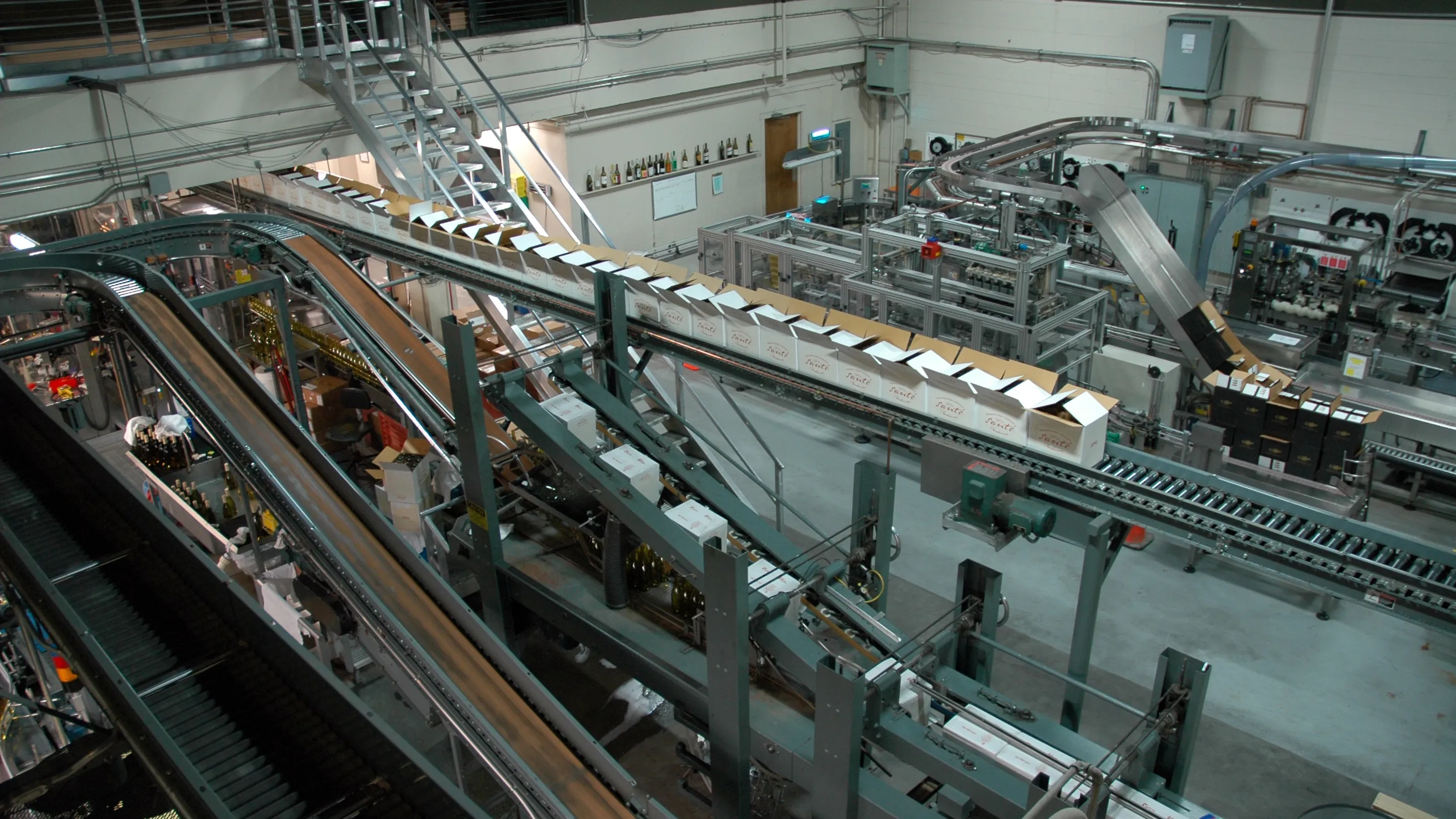 A bottling line from above: conveyors of bottles winding between filling and labelling machines.