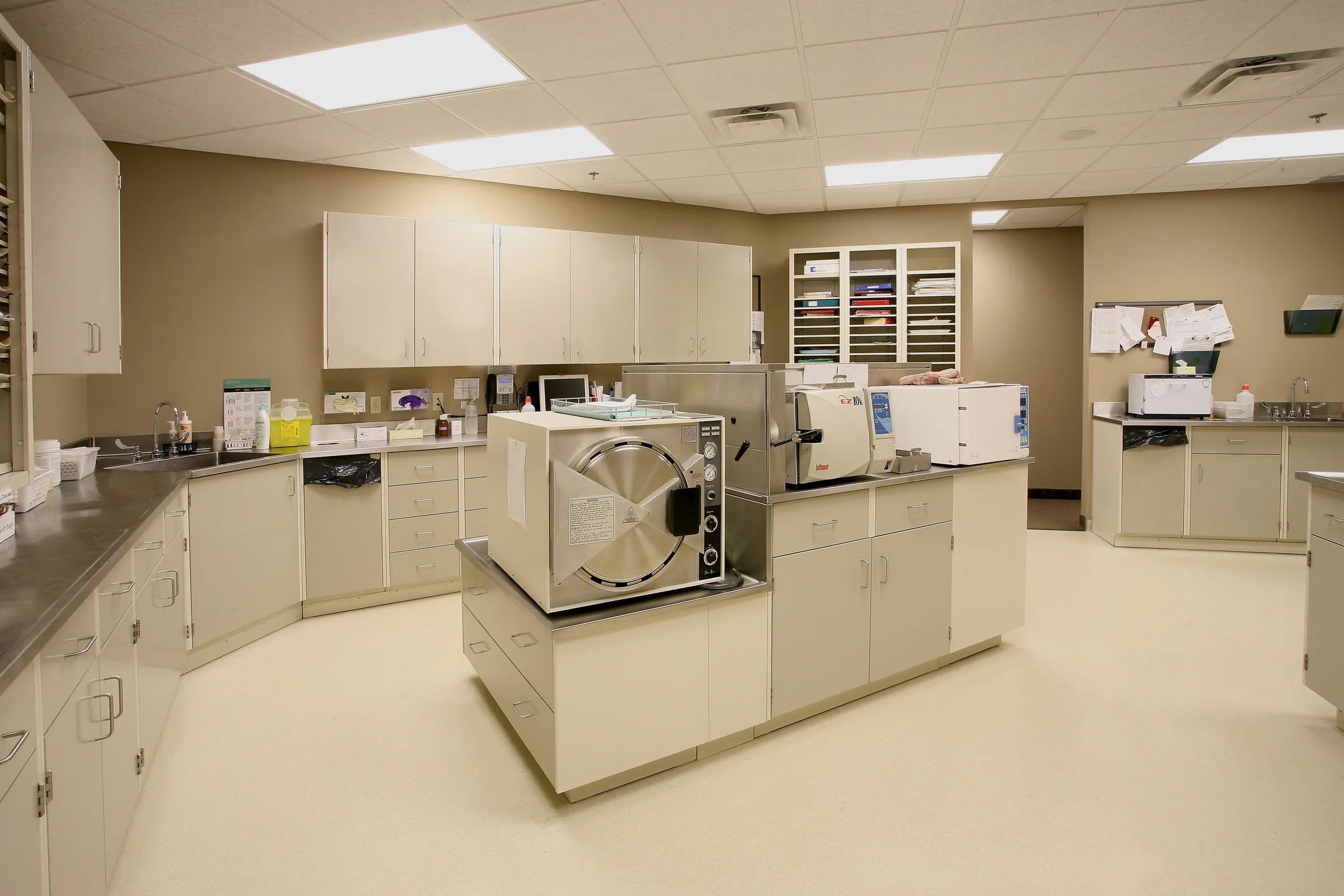 A dental sterilization room: an autoclave on a central island, cabinets and counters around it.