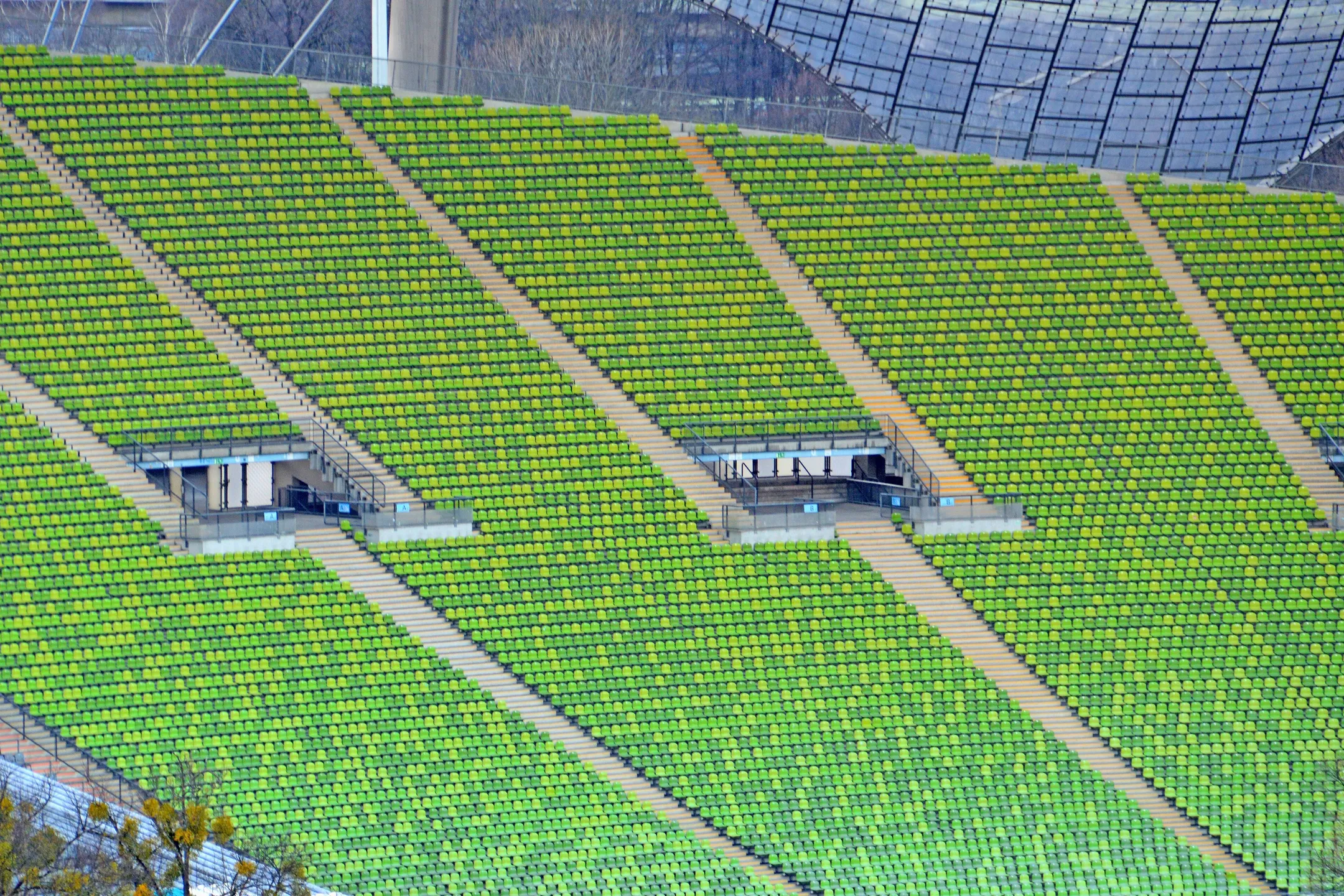 Rows of bright green stadium seats stepping down a slope, cut by aisles and two press boxes.